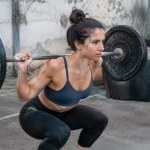 Femme accroupie barre metal lourde epaules tendues
