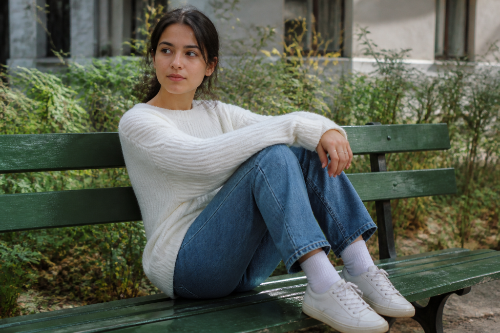 Baskets blanches et pull en maille sur un banc